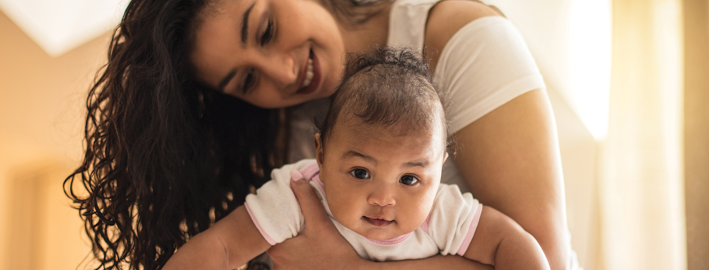 Woman holding smiling baby on tummy