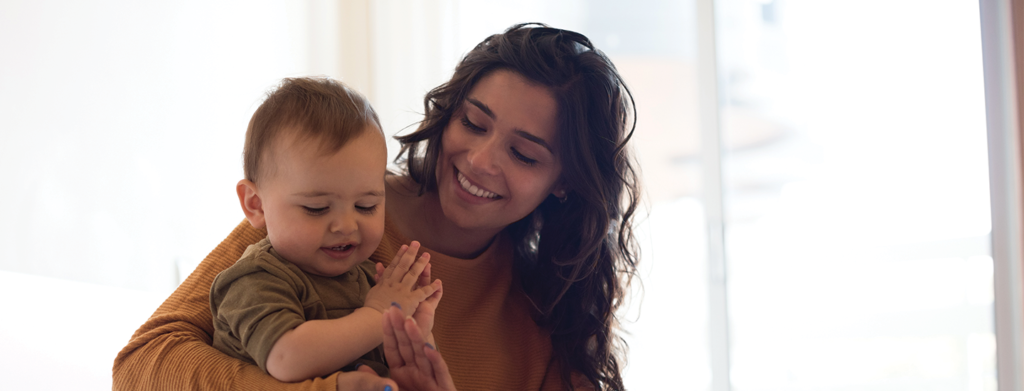 Mother holding baby clapping