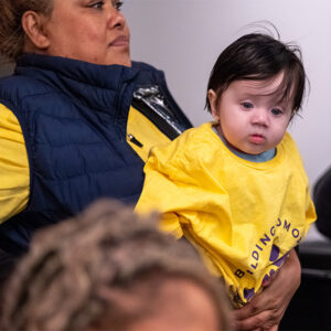 Baby in yellow advocacy day shirt sitting on mom's lap